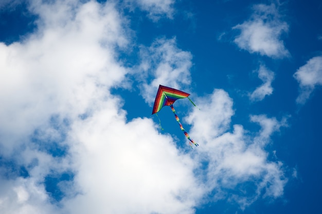 Cerf-volant de couleurs arc-en-ciel volant dans le ciel clair avec des nuages au jour d'été