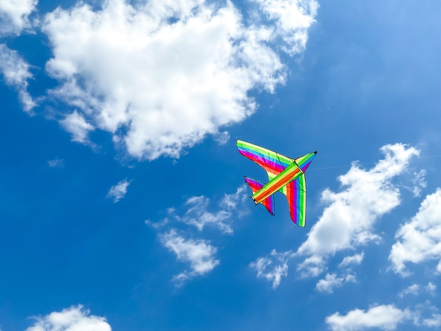 Un cerf-volant multicolore vole dans le ciel bleu par une journée ensoleillée Espace vide pour une inscription multicolore