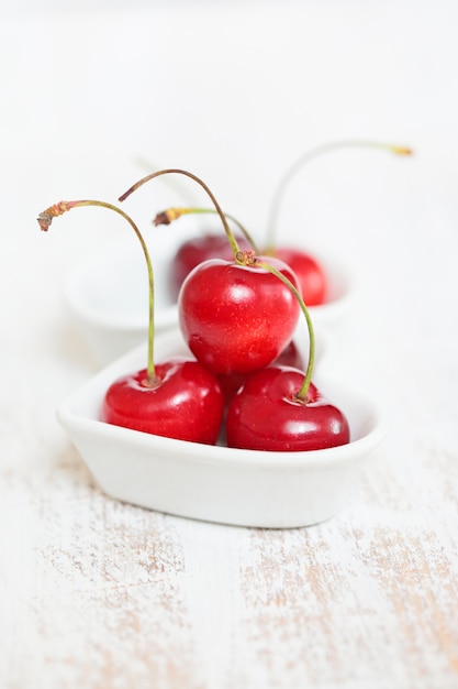 cerise dans une petite assiette blanche sur un tableau blanc minable sur blanc