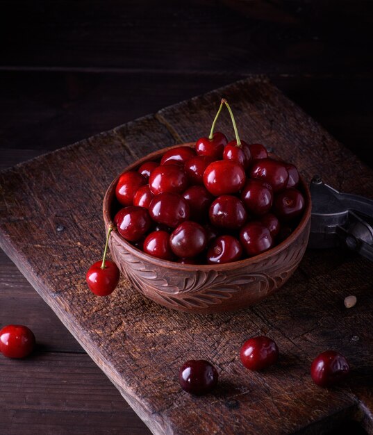 Cerise douce juteuse rouge mûre dans un bol d'argile brune sur une table en bois, Close up