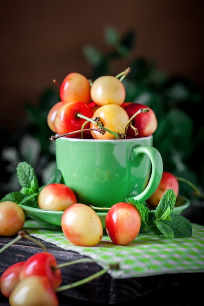 Cerise fraîche dans une tasse sur une table en bois rustique foncé