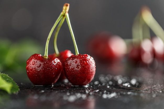 Cerise fraîche avec des gouttes d'eau sur une table sombre.