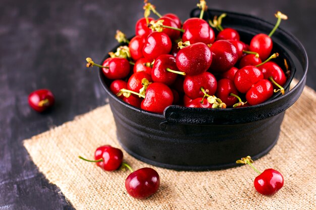 Cerise fraîche sur une table en bois noire. Baies mûres sucrées en gouttelettes d'eau