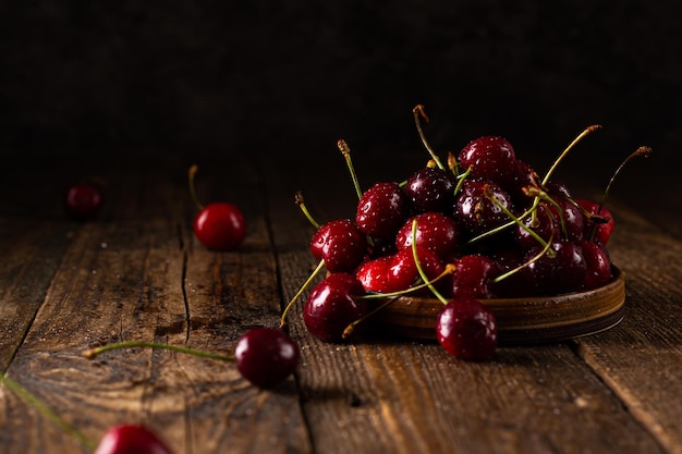 Cerise avec des gouttes d'eau sur une plaque en céramique sur une table en bois marron foncé