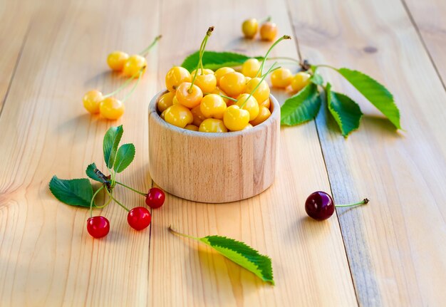 Cerise jaune et rouge sur une table en bois.