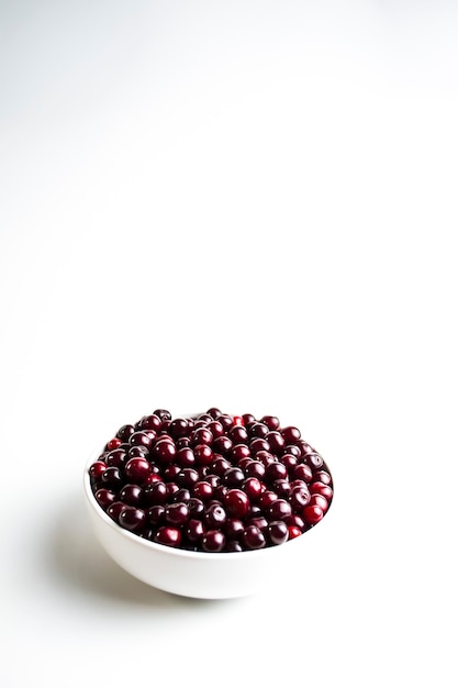 cerise rouge foncé dans une tasse blanche sur fond blanc