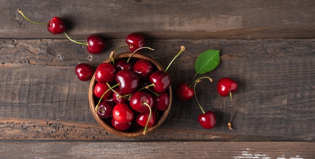 Cerise rouge fraîche dans un bol sur la vieille table en bois