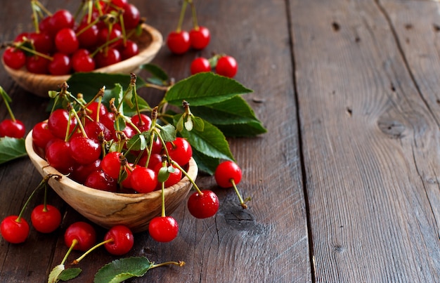 Cerises aigres fraîches dans des bols sur une table en bois