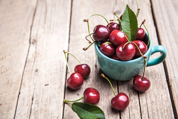 Cerises dans la belle tasse turquoise sur table en bois, fruits, baies