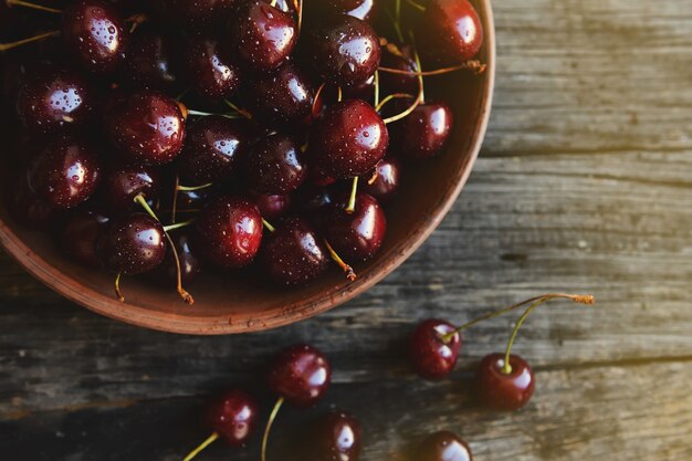 Cerises dans un bol en céramique sur une table en bois