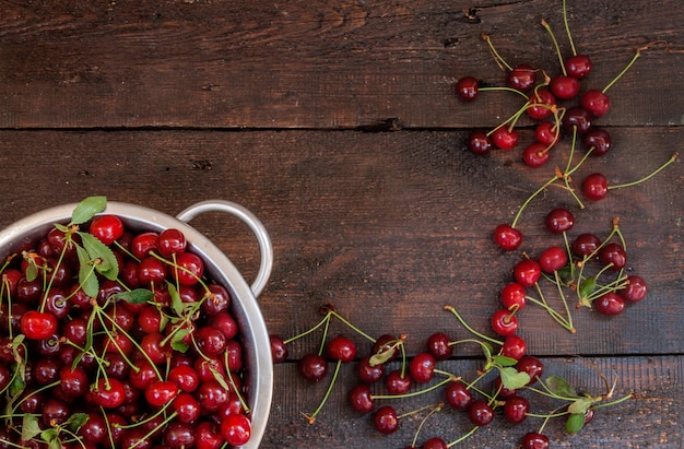 Cerises dans une passoire sur un fond en bois