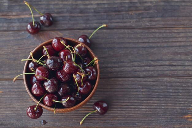 Cerises douces fraîches dans un bol en bois sur une table rustique