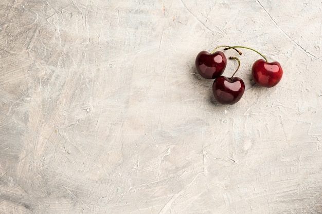 Cerises douces mûres dans un bol en céramique à la surface du béton