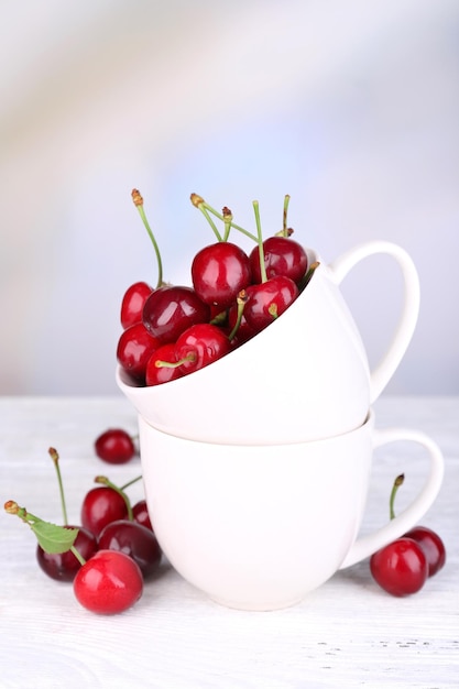 Cerises douces mûres dans une tasse sur une table en bois