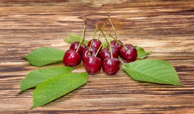 Cerises avec des feuilles sur le fond en bois