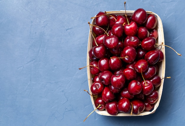 Cerises fraîches dans une boîte en bois avec espace pour le texte sur fond gris.