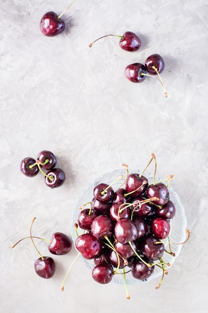 Cerises fraîches mûres dans un bol en verre sur fond gris. Vue de dessus