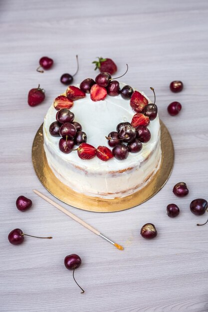 Des cerises et des fraises avec de l'or comestible sur un gâteau au fromage avec de la noix de coco