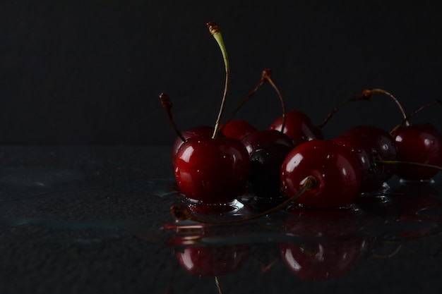 Cerises, avec des gouttes d'eau sur fond noir avec reflet