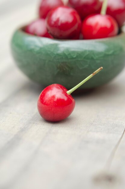 cerises gros plan dans un bol vert fruits rouges sur bois