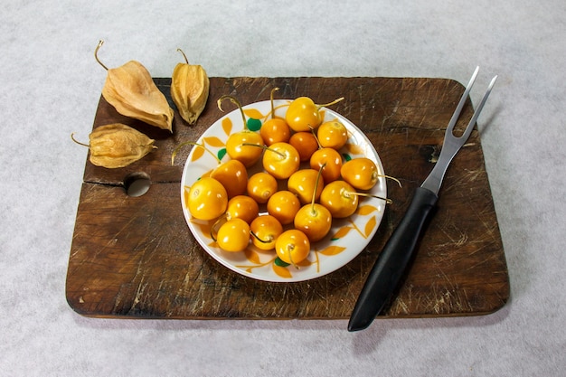 Cerises d'hiver fraîches Physalis groseille du Cap Aguaymanto Uvilla sur une assiette et à côté d'une fourchette