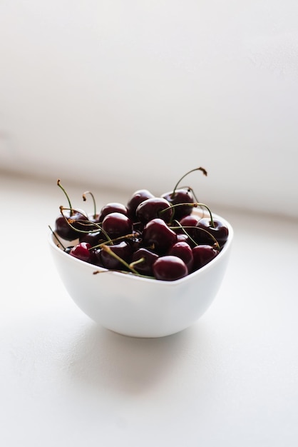 Cerises mûres fraîches sur une assiette sur fond blanc Vitamines et alimentation saine