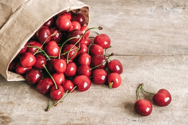 Cerises mûres fraîches dans un sac en papier sur fond de bois Vue de dessus Copier l'espace vide pour le texte