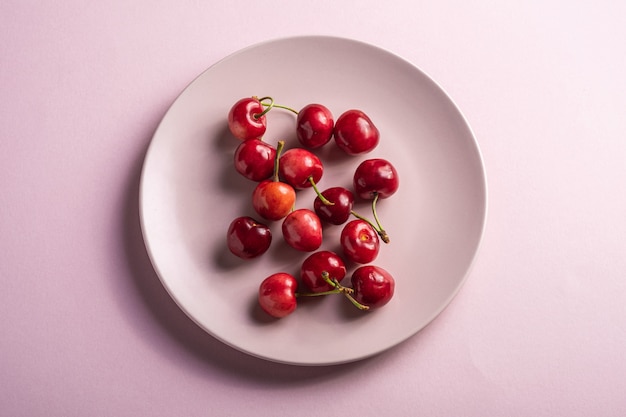 Photo cerises mûres fraîches sur une plaque rose, baies de vitamines d'été sur un minimum