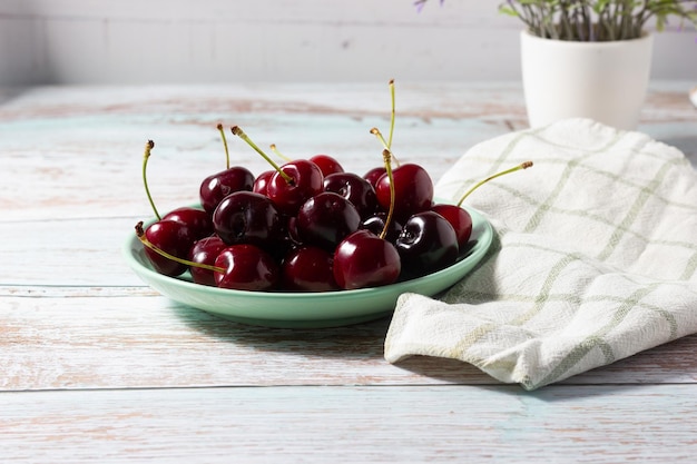 Cerises mûres sur une plaque verte sur un fond en bois