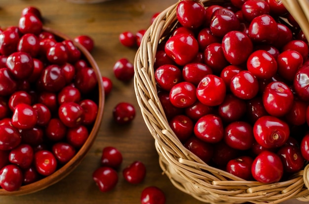 Cerises mûres rouges dans un panier en osier nature morte sur une table en bois mise à plat vue de dessus arrière-plan