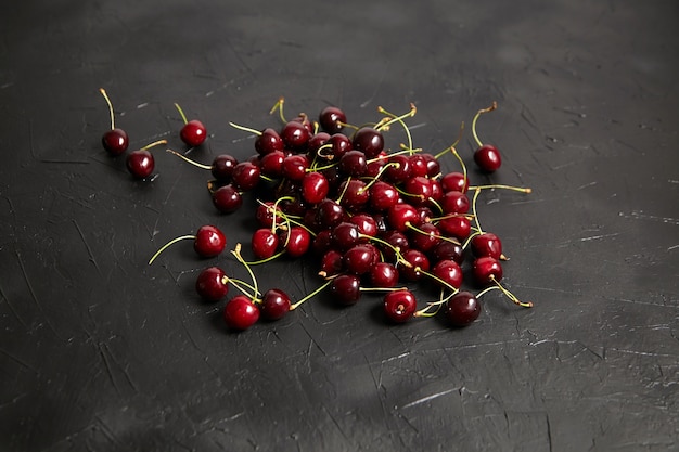 Cerises mûres rouges éparpillées sur un tableau noir