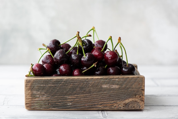 Cerises noires mûres sur branche dans une boîte en bois