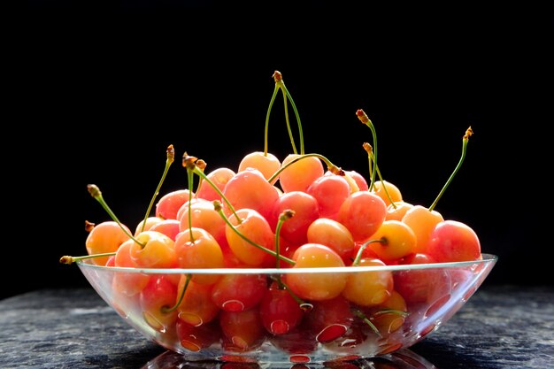 Cerises en plaque de verre sur la table en marbre sur un mur noir