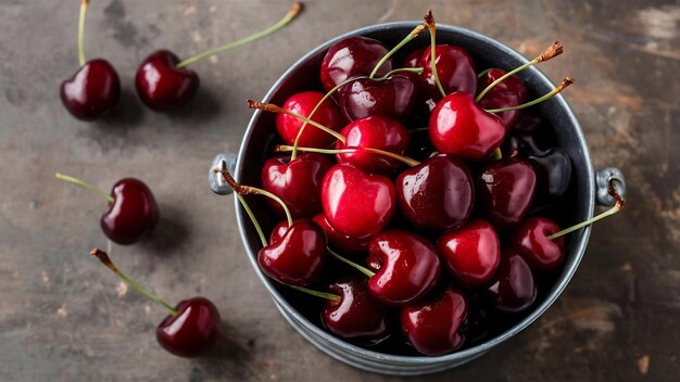 Photo des cerises de rosée dans un seau en métal près d'une table grise grincheuse