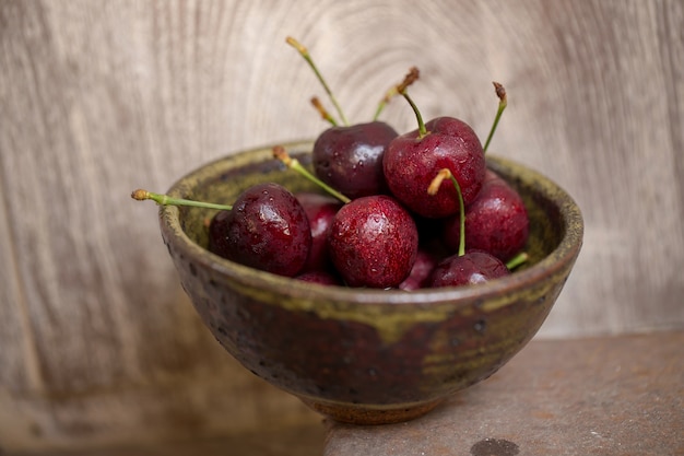 Cerises rouges dans un bol sur fond en bois