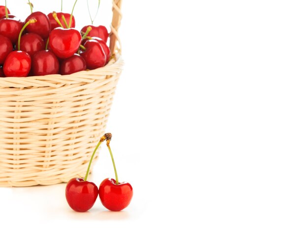 Cerises rouges saines dans un panier en osier isolé sur fond blanc