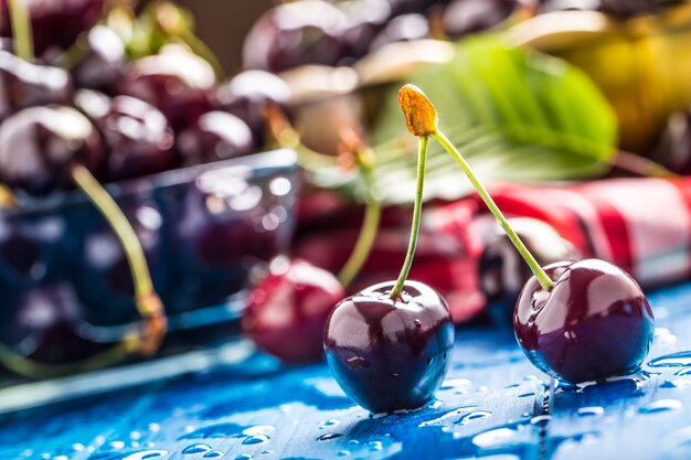 Cerises sucrées mûres sur table en bois bleu avec des gouttes d'eau.