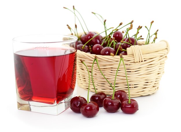 Cerises et un verre de jus de cerise isolé sur blanc