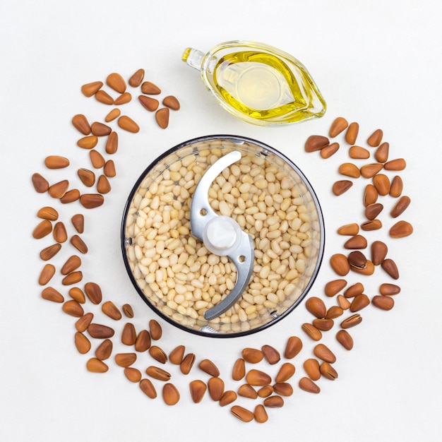 Cerneaux de pignons de pin dans un bocal mélangeur. Pignons de pin non décortiqués. L'huile de cèdre. Fond blanc. Mise à plat