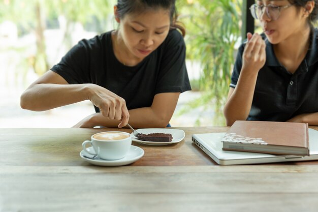 Certaines amies foceus choisies aiment manger un gâteau au brownie dans un café.