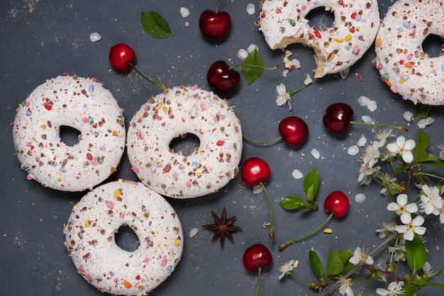 Certains beignets avec des cerises sur la table grise avec des fleurs vue de dessus fleur