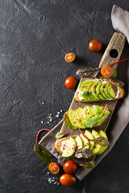 Certains grillés à l'avocat vert sur béton noir, vertical