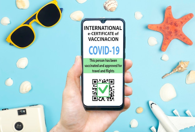 Certificat de vaccination contre le coronavirus ou passeport de vaccin pour le concept de voyageurs. Passeport électronique d'immunité COVID-19 dans l'application mobile pour smartphone pour les voyages internationaux. Fond bleu avec des lunettes de soleil,