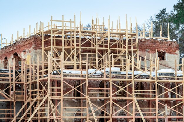 Échafaudage autour du bâtiment en briques rouges Restauration de la maison après la destruction globale