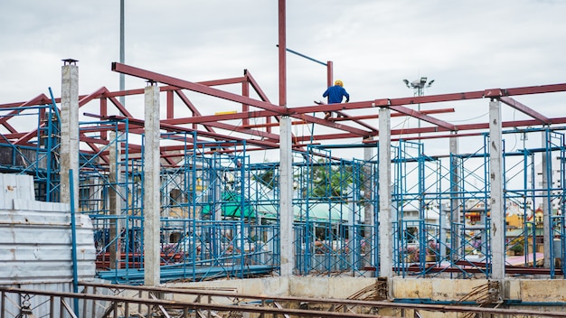 Échafaudage de maison, rénovation avec des ouvriers du bâtiment flou sur un échafaudage et du matériel au sol,