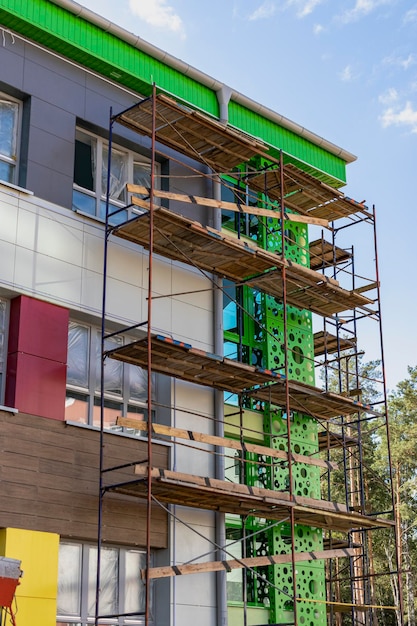 Échafaudages et échafaudages avec terrasses en bois, contre un ciel bleu. Réalisation de travaux de construction en hauteur. Sécurité des chantiers.