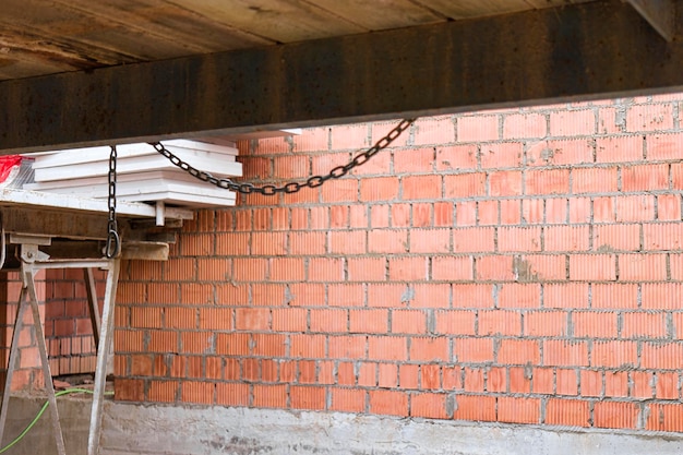 Échafaudages renforcés pour le travail des maçons dans la construction de murs en briques Vêtements pour le travail sur le chantier et le stockage des matériaux Gros plan Construction de murs en briques