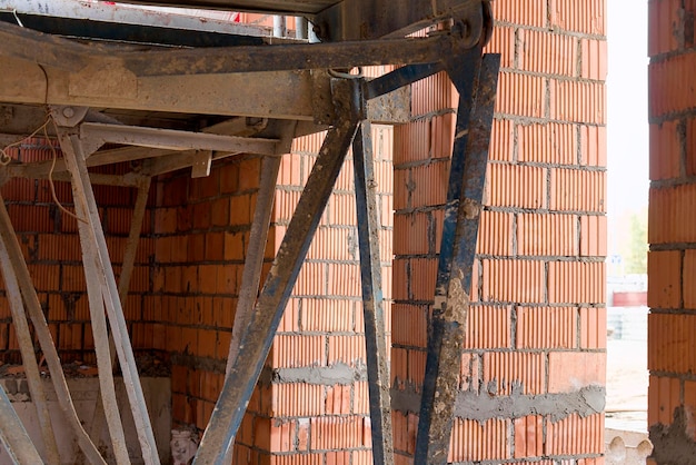 Échafaudages renforcés pour le travail des maçons dans la construction de murs en briques Vêtements pour le travail sur le chantier et le stockage des matériaux Gros plan Construction de murs en briques