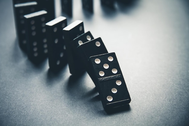 Chaîne de dominos noirs sur un fond de table Concept d'effet Domino