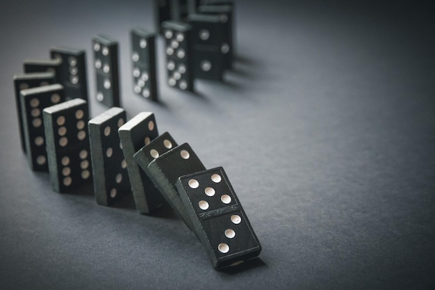Chaîne de dominos noirs sur fond de table sombre